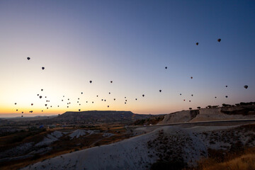 Hot air balloon flying over rocky landscape at sunrise in Cappadocia. Turkey