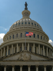 Fototapeta premium American flag waving on a flagpole against Congress and clear blue sky. US flag fluttering in the wind near Congress. USA, US waving flag, American flag.