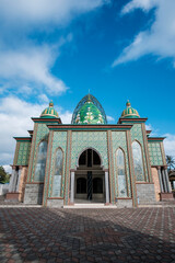 Modern Islamic Mosque with Green Glass Dome and Golden Geometric Patterns Against Blue Sky