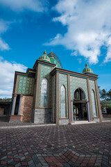 Ornate Mosque with Green and Gold Geometric Patterns and Majestic Domes under Blue Sky