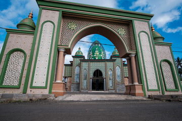 Ornate Green Islamic Mosque Entrance Gate with Calligraphy and Domes under Blue Sky
