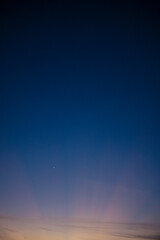 Dramatic Twilight Sky with Crescent Moon and Vibrant Crepuscular Rays at Dusk
