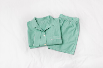 Green striped Pajama Set on white sheet background. Top view home sleepwear female from soft cotton...