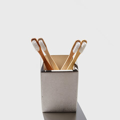 Aesthetic Beige bamboo toothbrushes with white bristles in toothbrush holder at sunlight on light background, copyspace. Simplicity, hygiene, and environmentally friendly alternatives, side