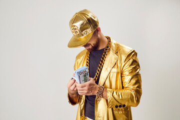 A rich man in a gold jacket holds a wad of dollars, close-up. Concept of quick get rich schemes, cryptocurrency trading, profit. An eccentric image of a financial manipulator, broker