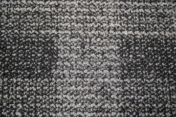 A close-up shot displays a textured carpet with mottled grey and black fibers. It emphasizes the material's depth and the interplay of dark and light, creating a sense of cozy comfort.