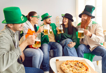 Saint Patrick day friend home party, celebration of national Irish culture with pizza, beer. Group of funny dressed people with Irish drink, wearing silly green hat, beard, happy social entertainment