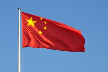Naklejka premium Chinese flag waving proudly against a clear blue sky, representing national pride and freedom.