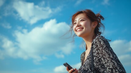 Young Asian woman smiling while holding cellphone and looking at blue sky,copy space,banner.