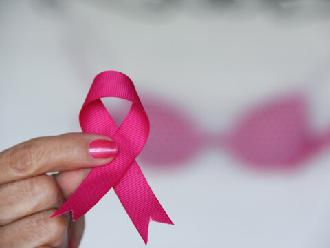 Selective focus of woman holding pink ribbon with pink bra in the background for Brest Cancer Awareness Month concept in October.  - Powered by Adobe