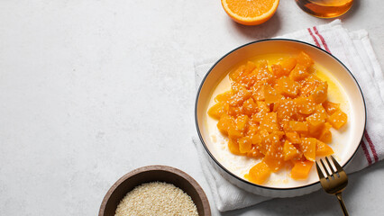 Healthy dessert with sliced pumpkin, honey and orange juice in a bowl. Pumpkin dish. Copy space