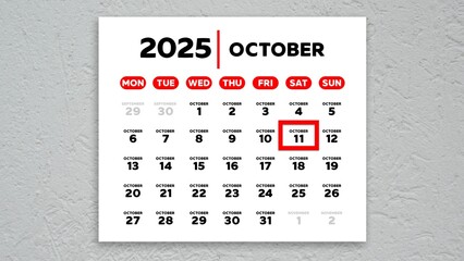 The date October 11th marked with a red cursor on the wall calendar 2025