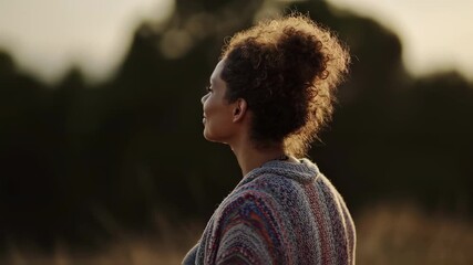 Medium shot of a pregnant woman practicing gentle breathing exercises calm face and belly in focus against softly blurred nature behind.