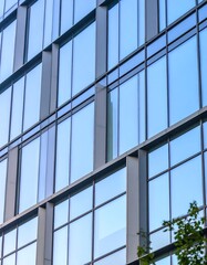 Modern glass facade reflecting blue sky; grid pattern