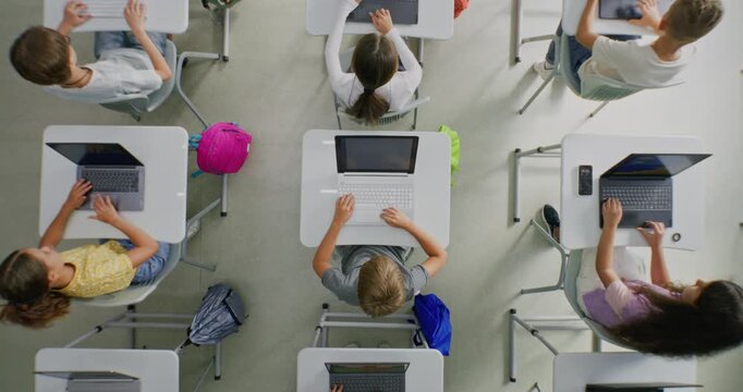 Primary School Students Working on Creative Projects on Laptops, Practicing Digital Skills in Art Class. Young Kids Drawing, Creating Pictures on Digital Devices. Interactive STEM Learning. Top View.