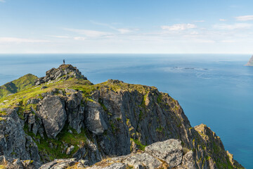 Stornappstinden mountain summit during summer. A hiker is standing on the peak , looking at the amazing landscape. Great hiking trail on Lofoten islands, beautiful hiking destination. Norway fjords.