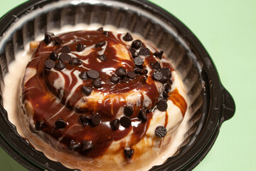 A macro close up of a cinnamon bun with chocolate chip toppings