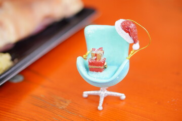 Miniature Christmas Ornament with Blue Chair, Santa Hat, and Red Gift Boxes, Festive Holiday Decoration Symbolizing Celebration and Winter Cheer