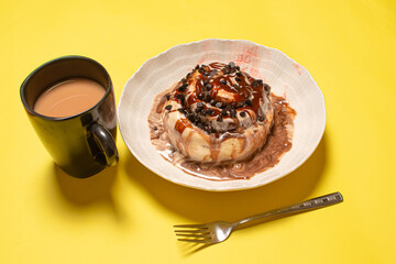 A chocolate chip cinnamon bun served with a cup of hot coffee