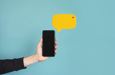 Hand holding smartphone with yellow speech bubble. Modern communication concept of phone messages, social media chat, and digital information exchange via internet. Global network connectivity.