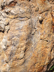 Close-up of large sandstone rock with rough texture and natural orange-brown surface details in sunlight.