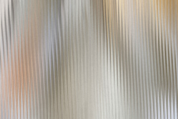 Fototapeta premium A textured background with vertical ribbed patterns, featuring a subtle gradient of metallic silver and warm copper tones