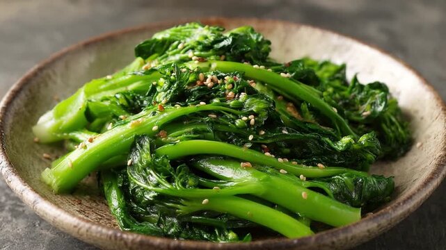 Stir-fried Gai Lan with Sesame Seeds: A vibrant and healthy dish of stir-fried gai lan (Chinese broccoli) is artfully arranged on a rustic plate, sprinkled with toasted sesame seeds.