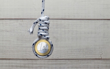 A one euro coin symbolically hanging in a noose, representing the european financial crisis and economic struggles.