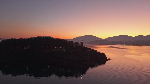 Orbiting the Kaki Kefali Lighthouse in Chalkida during twilight, capturing its guiding beacon shining over the sea and coastline