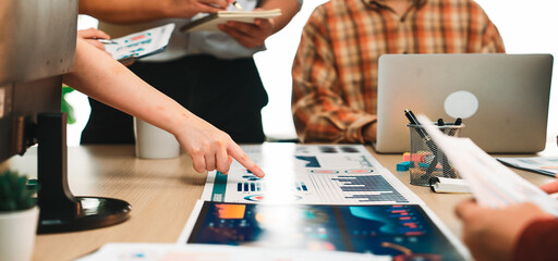 A diverse team engages in a detailed analysis of various data charts, using laptops and notepads in a modern office, highlighting collaborative business strategies. SACTR