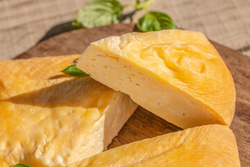 Close-up of smoked cheese wheel with a cut wedge on wooden board