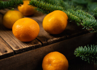 Ripe juicy clementines tangerines on the wooden background with fir branches. Cozy winter mood.
