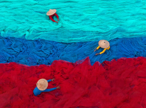 Unidentified fishermen arranging colourful  fish nets. Top view, selective focus.