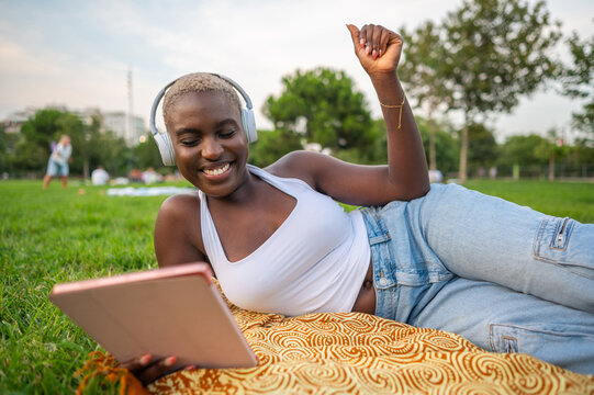 Young woman listening music with headphones and tablet in a park