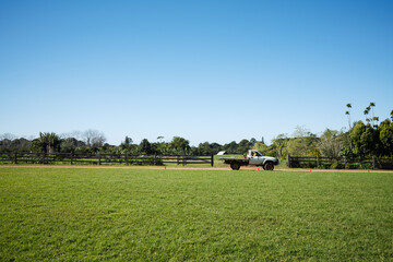 Fototapeta premium Farmer driving pickup truck through green field on sunny day