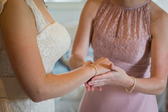 Bridesmaid Assisting Bride with Jewelry on Wedding Day
