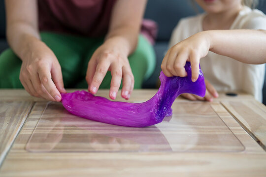 Girls kids holding playing with purple slime putty at home