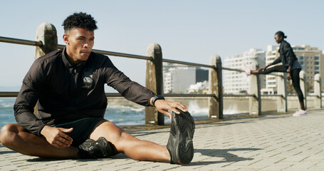 Obraz premium Man, fitness and stretching with leg for warm up or flexibility on outdoor promenade. Active, male person or runner with workout preparation or foot for physical exercise or training on sidewalk