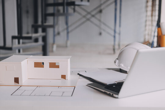 Construction manager and engineer dressed in orange work vests and hard helmets explore construction documentation on the building site near the steel frames