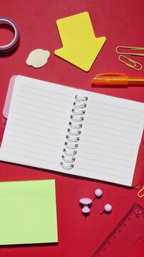 Stop motion supplies appear and vanish around spiral notebook that serves as copy space on red background