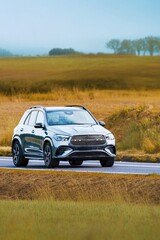Fototapeta premium Modern crossover SUV driving through green countryside