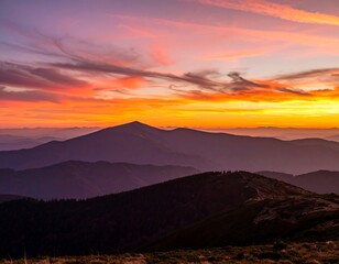 Vibrant sunset hues paint the sky over a range of silhouetted mountains