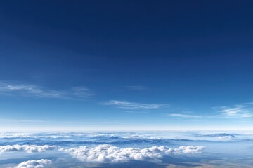 Obraz premium Vast blue sky over a layer of puffy white clouds, obscuring mountain peaks below. Horizon with sun glare