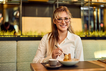 Smiling Woman Enjoying Dessert and Coffee in a Cozy Cafe