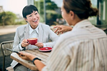 Business Women Conversing Over Coffee in an Outdoor Cafe with Relaxed Atmosphere