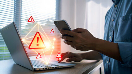 Alert businessman managing digital security threats on laptop and smartphone with glowing warning icons, representing cybersecurity risks.