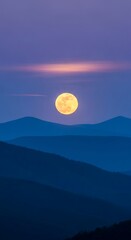 Full moon above layered mountain ranges at dusk.
