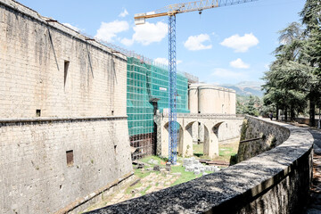 the massive stone walls of the Forte Spagnolo in L'Aquila, Italy, on a sunny day.