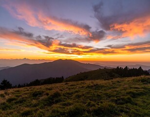 Obraz premium Fiery sunset over rolling hills and distant mountains