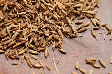 Aromatic cumin seeds on wooden rustic surface. Organic Asian spice. Macro